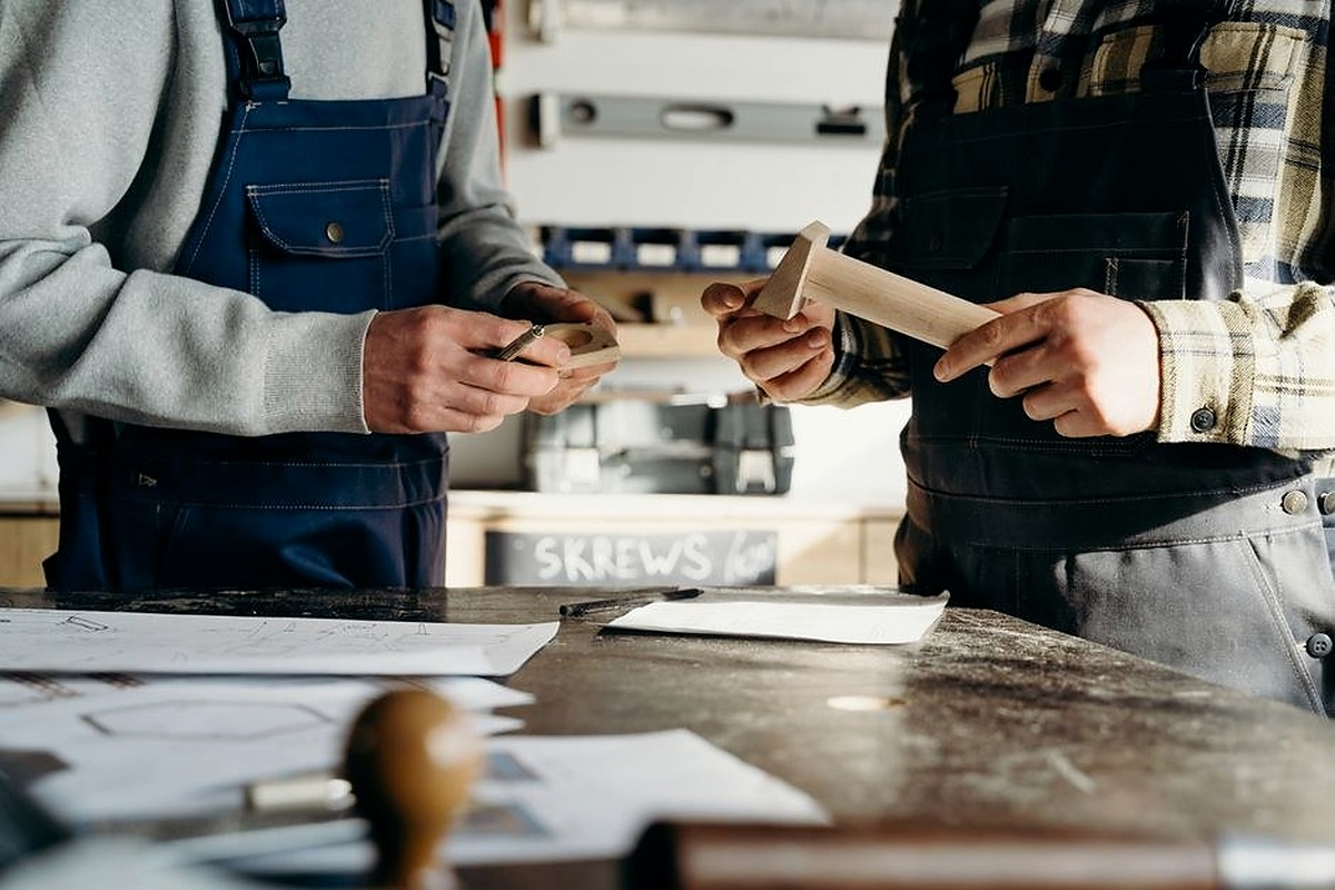 Two people working together with paper and tools at a shared table