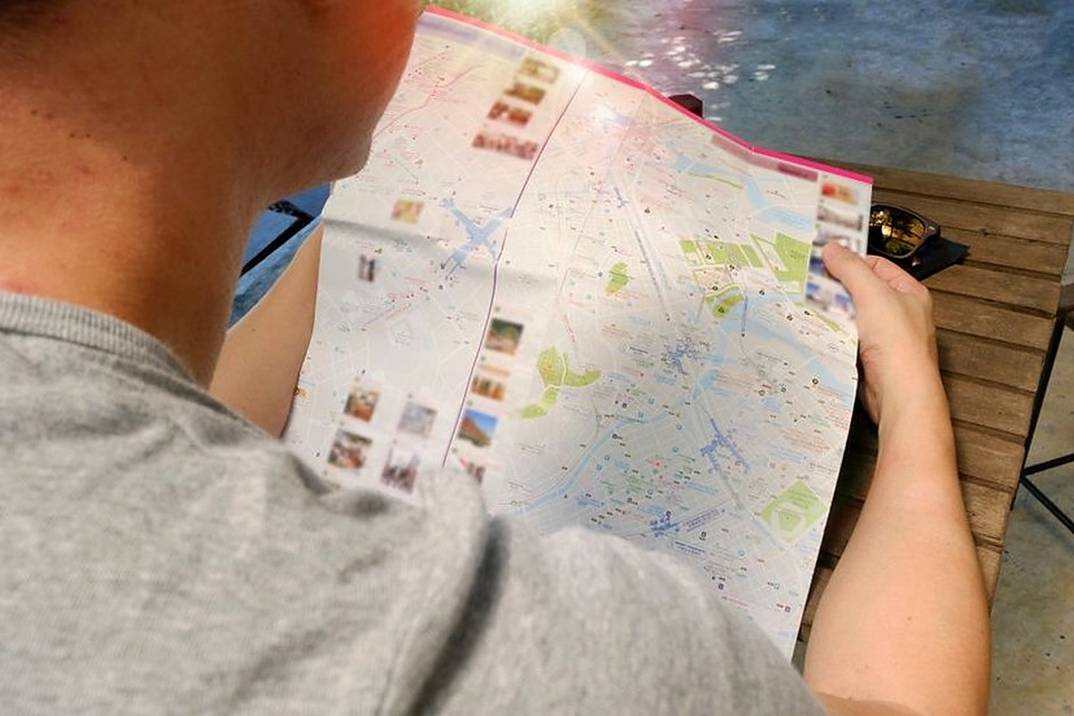 Traveler holding an open paper map while planning a day trip